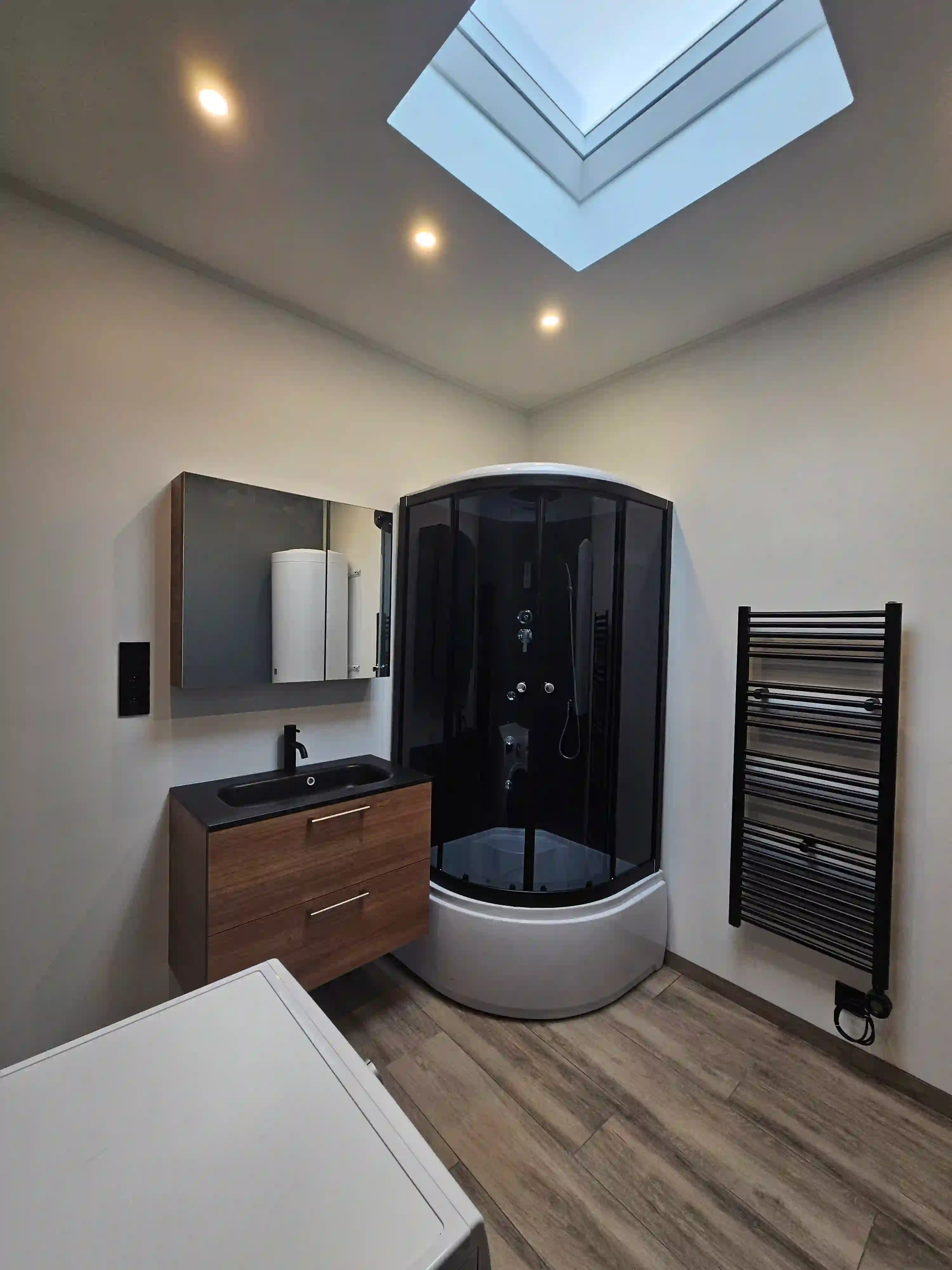 Afgewerkte badkamer met douche, meubel, radiator en spots